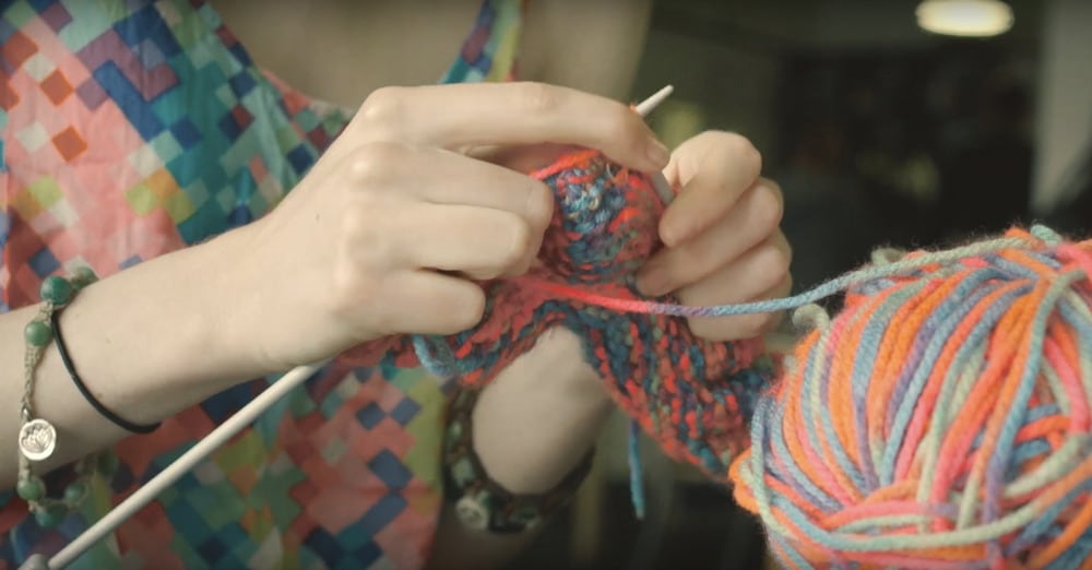 Close up of hands knitting a colourful yarn